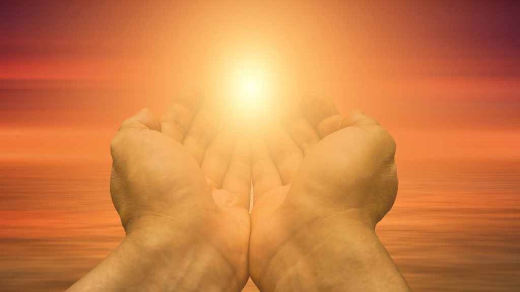Two hands outstretched toward the sun