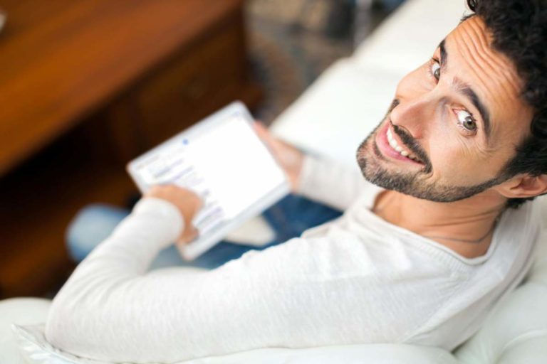 man sitting on sofa holding a laptop